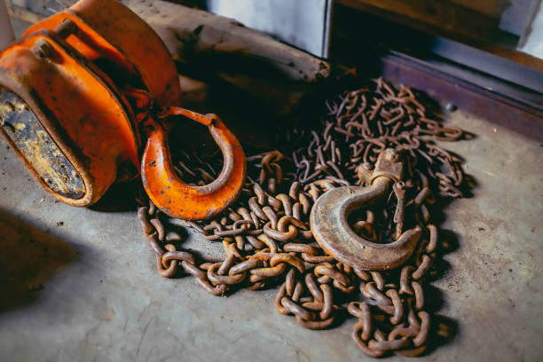 A rusty chain hoist lay on the cement floor of the workshop.