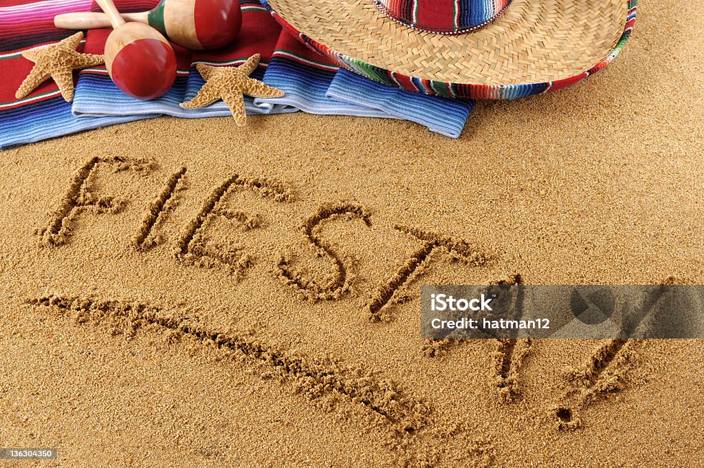 Fiesta beach writing The word Fiesta written on a sandy beach, with sombrero, traditional serape blanket, starfish and maracas (studio shot - warm color and directional light are intentional).  You can see my complete Mexican collection by CLICKING HERE.  Alternative version of this file shown below: Above Stock Photo