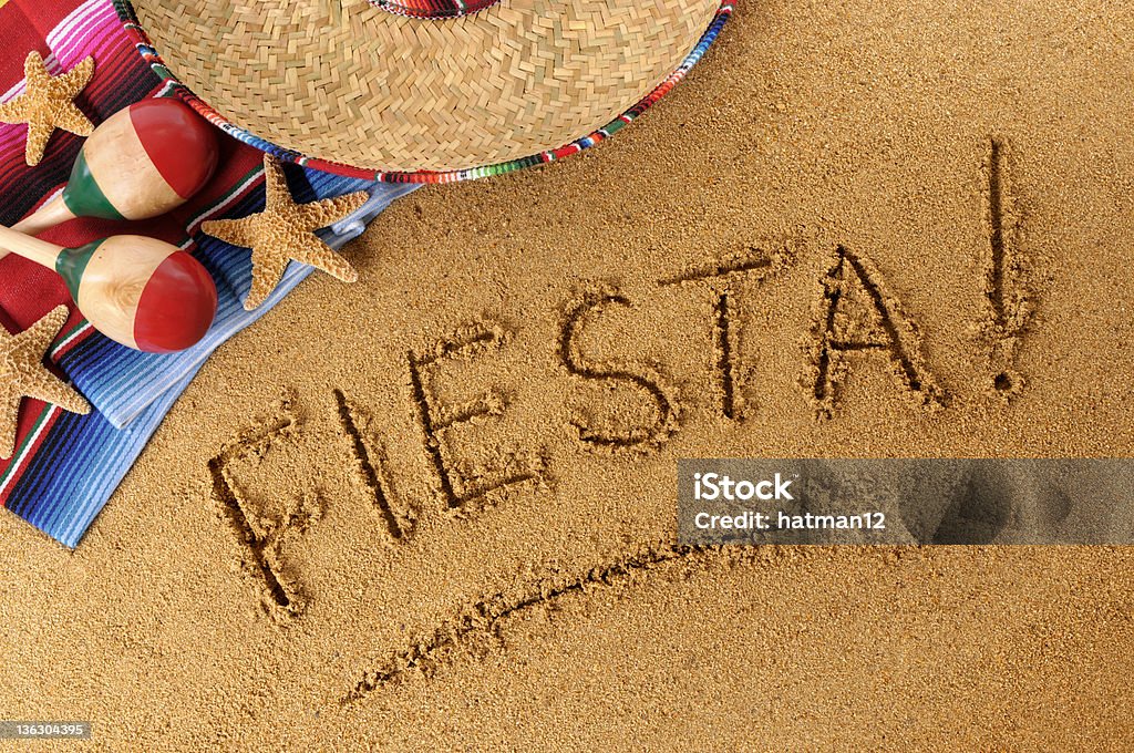 Fiesta beach writing The word Fiesta written on a sandy beach, with sombrero, traditional serape blanket, starfish and maracas (studio shot - warm color and directional light are intentional).  You can see my complete Mexican collection by CLICKING HERE.  Alternative version of this file shown below: Above Stock Photo
