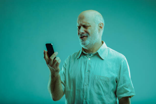 Bemused man looking at his smartphone in confusion as he hold it up to read a text message or watch media