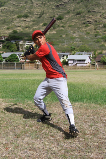 A hispanic baseball player stands ready to knock a baseball into the outfield