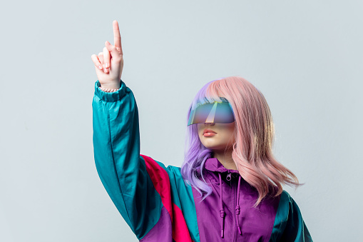 Teen girl in VR glasses and purple 80s tracksuit on gray background