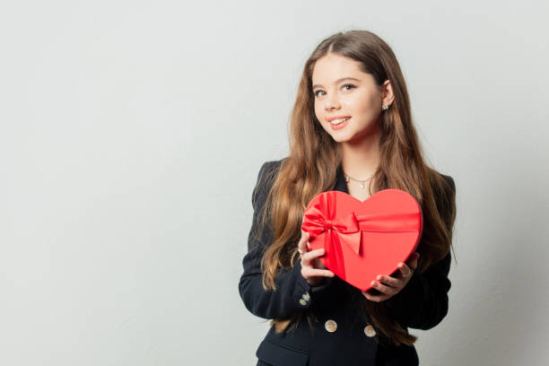istock Young girl with heart shape gift box on white background. 1363047110