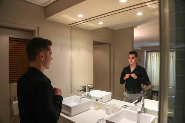 istock A Young man buttoning up his shirt in front of the mirror. 1363047757