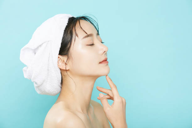 Beauty portrait of a young Asian woman with a towel wrapped around her head back ground body care and beauty stock pictures, royalty-free photos & images