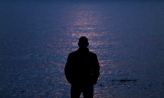 Silhouette of adult man looking at sea during sunset. Almeria, Spain