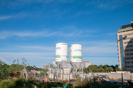 Cement Storage Silos in Industrial District of Valencia, Spain, with manufacturer names visible