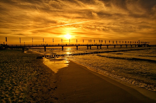 The pier in Zingst at sunset bathed in orange light