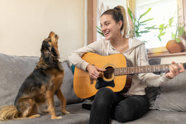 istock Young woman playing guitar while her dog is singing 1363064261
