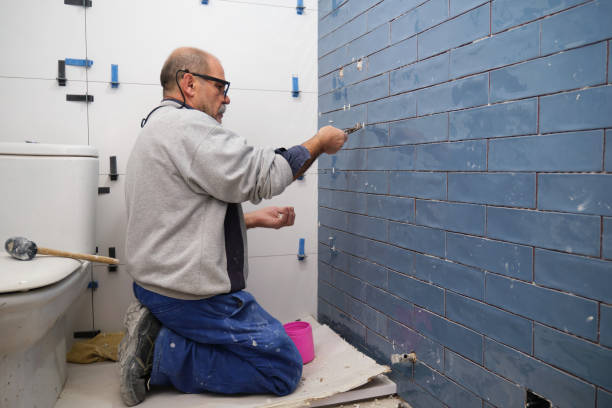 Senior constructor worker removing the separation between tiles on the wall. Senior constructor worker removing the separation between blue small ceramic tiles on the wall. Home renovation and building new house concept. mason craftsperson stock pictures, royalty-free photos & images