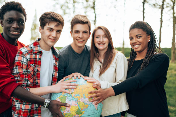 amigos multirraciales con el mundo en el parque - adolescence teenager globe map fotografías e imágenes de stock