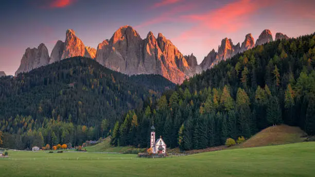 Panoramic image of  magical Dolomites mountains in a gorgeous Val di Funes valley,  South Tyrol, Italian Alps at autumn sunset.