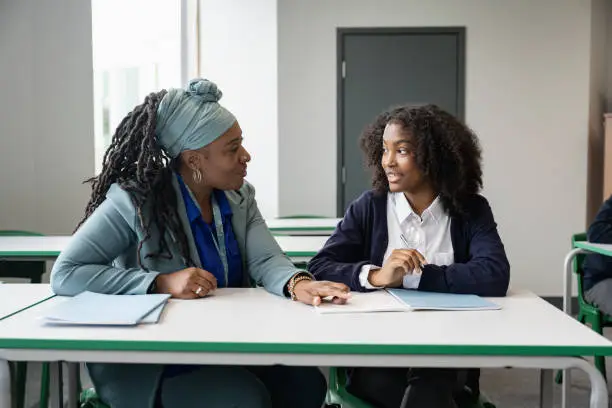 Photo of Black educator working with multiracial student in classroom