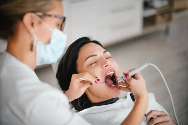Dentist removing dental calculus from the patient in the dental office.