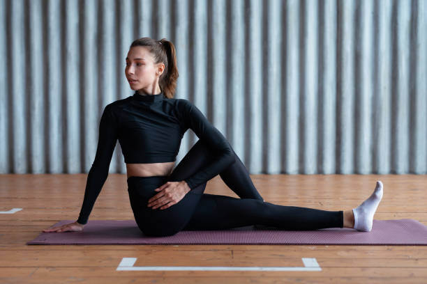 Fit woman working out, stretching while sitting on the floor Fit woman working out, stretching while sitting on the floor. twist pose stock pictures, royalty-free photos & images