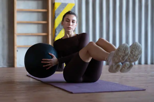 Photo of Woman doing russian twists with a medicine ball