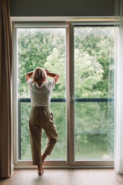 istock Depressed woman looking through the window 1363075829