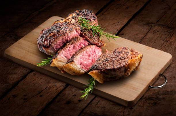 Fiorentina T-bone steak cut on rectangular wooden chopping board and vegetables Fiorentina T-bone steak cut on rectangular wooden chopping board isolated on rustic wooden background cut of meat stock pictures, royalty-free photos & images