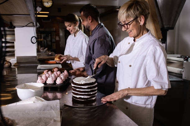istock Group of bakers in uniform decorating desserts in modern manufacturing. 1363079981