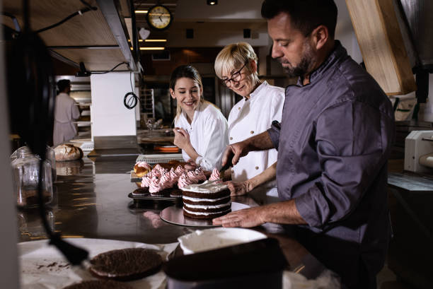 istock Group of bakers in uniform decorating desserts in modern manufacturing. 1363080001