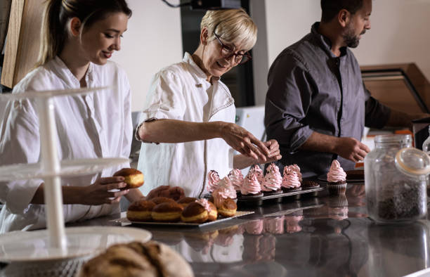 istock Group of bakers in uniform decorating desserts in modern manufacturing. 1363080079