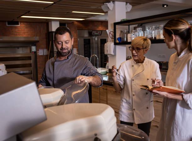 istock Group of bakers in uniform preparing dough for bread in modern manufacturing. 1363080739