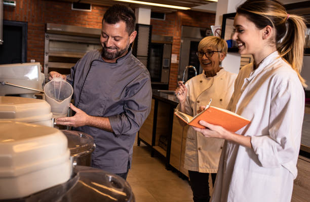 istock Group of bakers in uniform preparing dough for bread in modern manufacturing. 1363081118