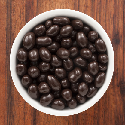Top view of white bowl full of dark chocolate covered peanuts