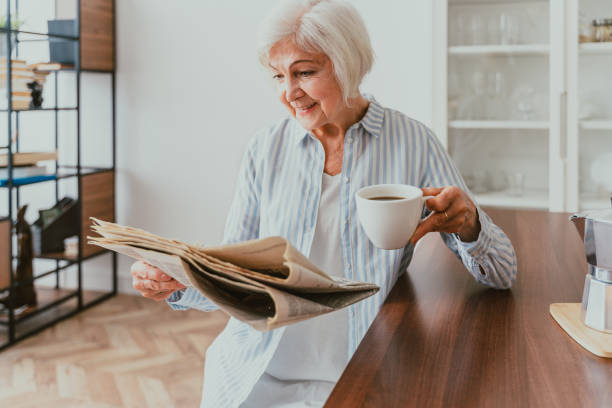 istock Elderly woman having breakfast and reading newspaper at home 1363084657