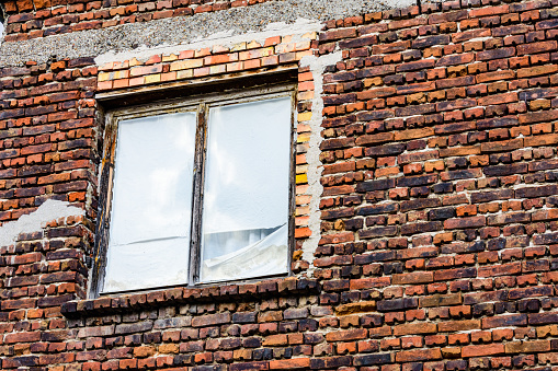 Window in red brick wall of ancient residential building