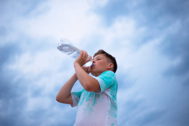 istock The boy drinks water from a plastic bottle. Portrait against the sky. Thirst. 1363086743