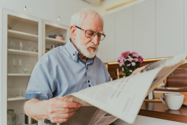 istock Elderly man having breakfast and reading newspaper at home 1363088593