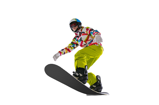 Roll on snowboard. Young woman in bright sportswear, goggles and helmet snowboarding isolated on white background. Concept of winter sports, active and healthy lifestyle, extreme sports and fashion