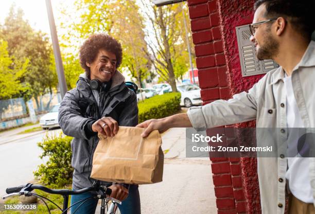 Male Courier With Bicycle Delivering Fast Food To The Customer In City Stock Photo - Download Image Now