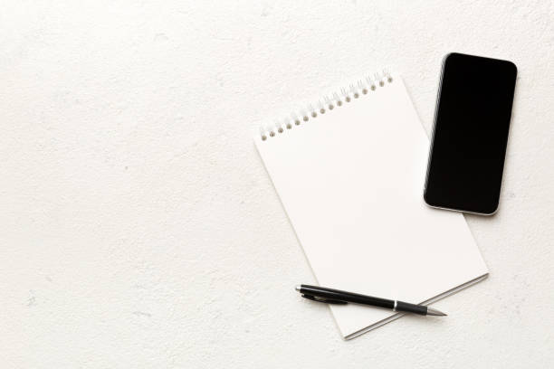 istock Smartphone with a notebook on a light Color background. top view 1363096937