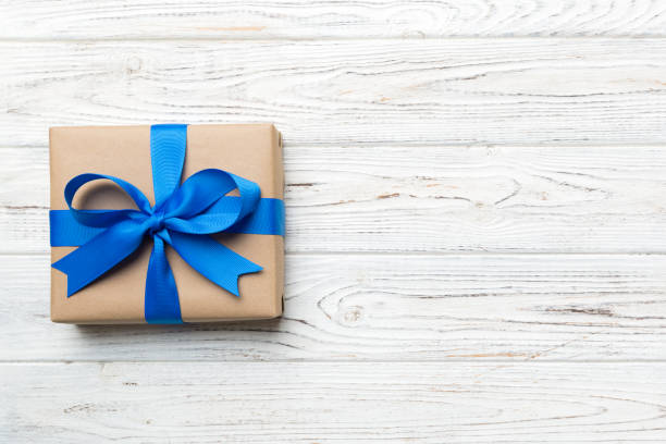 istock Holiday gift box wrapped in craft paper with colored bow on table background. Top view, flat lay, copy space 1363096940