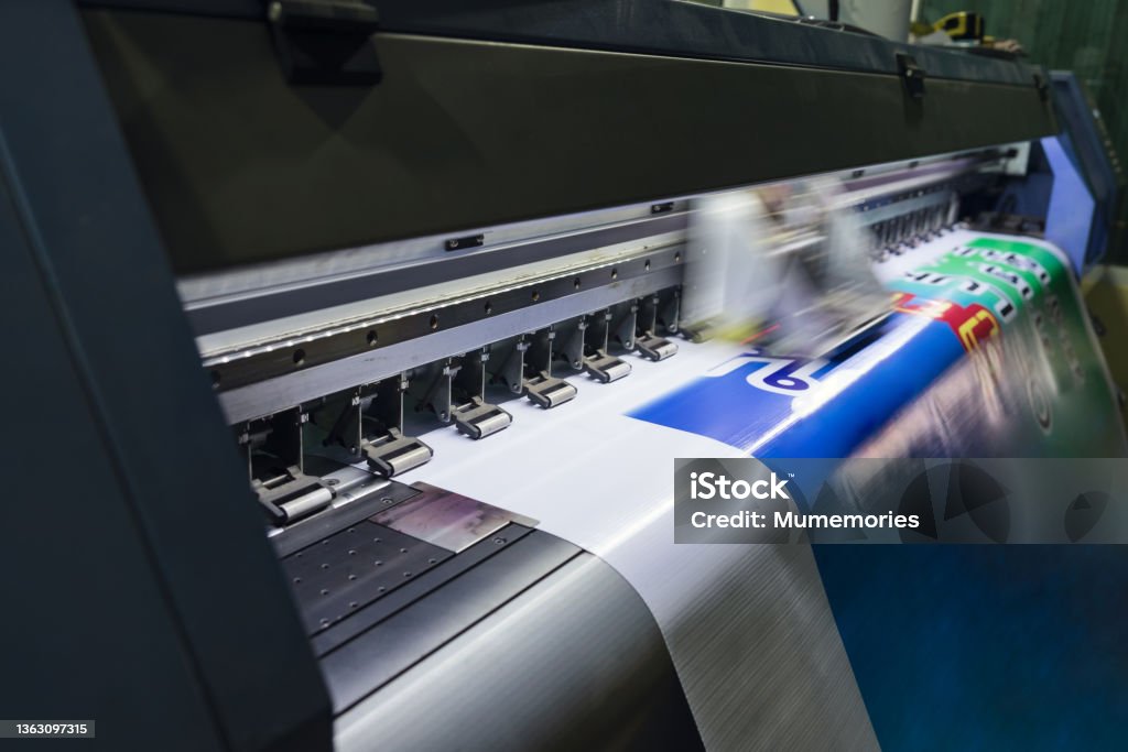 Large format inkjet printer working on vinyl paper in workplace Large format inkjet printer machine working on vinyl paper in workplace Printing Out Stock Photo