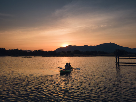 Tourists paddling in canoe on the lake and sunset over mountain view