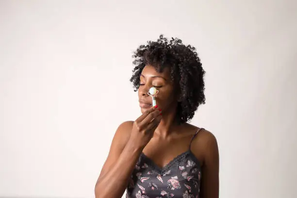 Black woman showing how to use a stone face roller