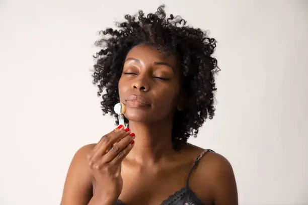 Black woman showing how to use a stone face roller