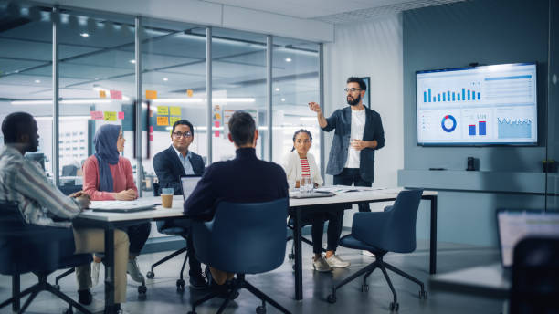 diverses modernes büro: geschäftsmann führt geschäftstreffen mit managern, spricht, nutzt präsentationsfernsehen mit statistiken, infografiken. digitale unternehmer arbeiten am e-commerce-projekt. - investment stock-fotos und bilder