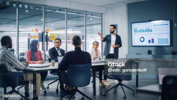 Diverse Modern Office Businessman Leads Business Meeting With Managers Talks Uses Presentation Tv With Statistics Infographics Digital Entrepreneurs Work On Ecommerce Project Stock Photo - Download Image Now