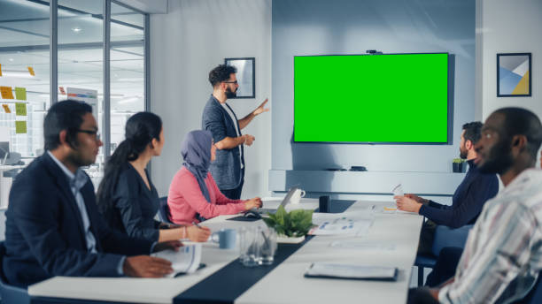 Office Conference Room Meeting Presentation: Hispanic Businessman Talks, Uses Green Screen Chroma Key Wall TV. Successfully Presenting a Product to Group of Multi-Ethnic Investors. e-Commerce Strategy presentación de la reunión de la sala de conferencias de la oficina: empresario hispano habla, usa tv de pared chroma key de pantalla verde. presentación exitosa de un producto a un grupo de inversores multiétnicos. estrategia de comercio electrónico