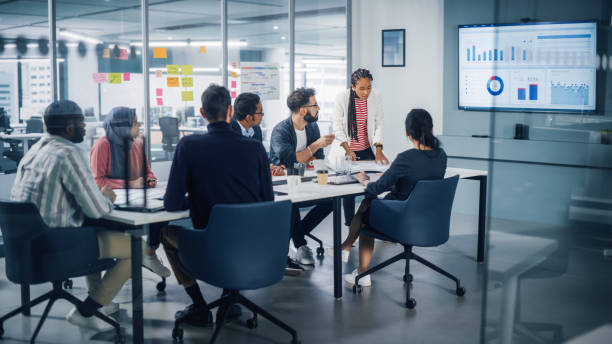 istock Multi-Ethnic Office Conference Room Meeting: Diverse Team of Creative Entrepreneurs, Specialists Talk, Use TV for infographics. Businesspeople work on Digital e-Commerce Startup. 1363104969