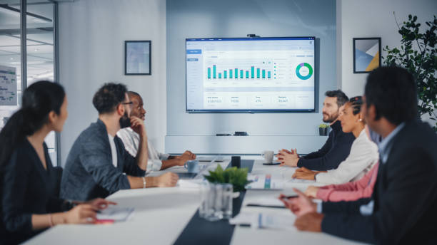 istock Multi-Ethnic Office Conference Room Meeting: Diverse Team of Managers, Executives Talk, Uses Wall TV with Big Data Analysis, Charts and Infographics. Businesspeople Investing in e Commerce Startup 1363105073