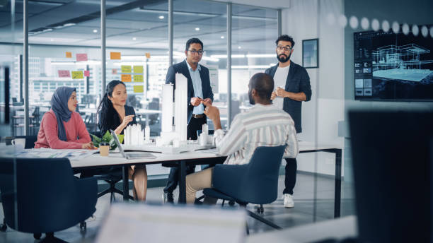 istock Modern Multi-Ethnic Architectural Agency Office Meeting. Group of Professional Architects, Designers, Developers, Investors Use TV with 3D Building Model to Design Sustainable Housing Project 1363105083