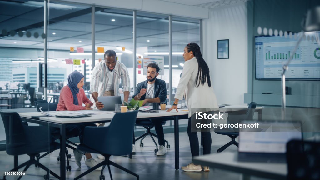 Multi-Ethnic Office Conference Room Meeting: Multicultural Team of Four Creative Entrepreneurs Talk, Discuss Growth Strategy. Diverse Young Businesspeople work on Digital e-Commerce Startup. Office Stock Photo