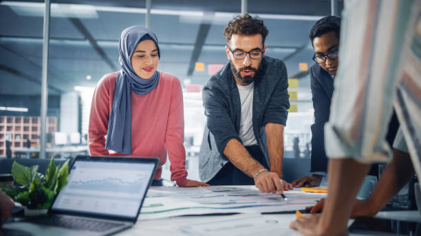 istock Multi-Ethnic Office Conference Room Businesspeople Meeting Gather Around Table. Diverse Team of Creative Professionals Talk, Brainstorms, work in Innovative Digital e-Commerce Startup. 1363105138