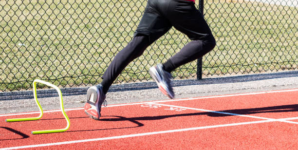 istock Runner sprinting past yellow mini hurdle on a red track 1363106247