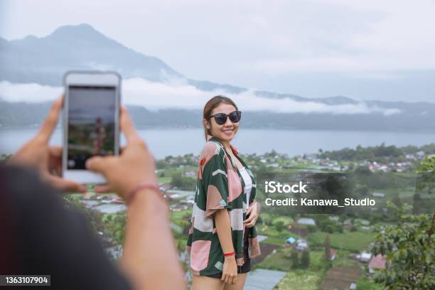 Insta Boyfriend Photographing Girlfriend With Mountain View Stock Photo - Download Image Now